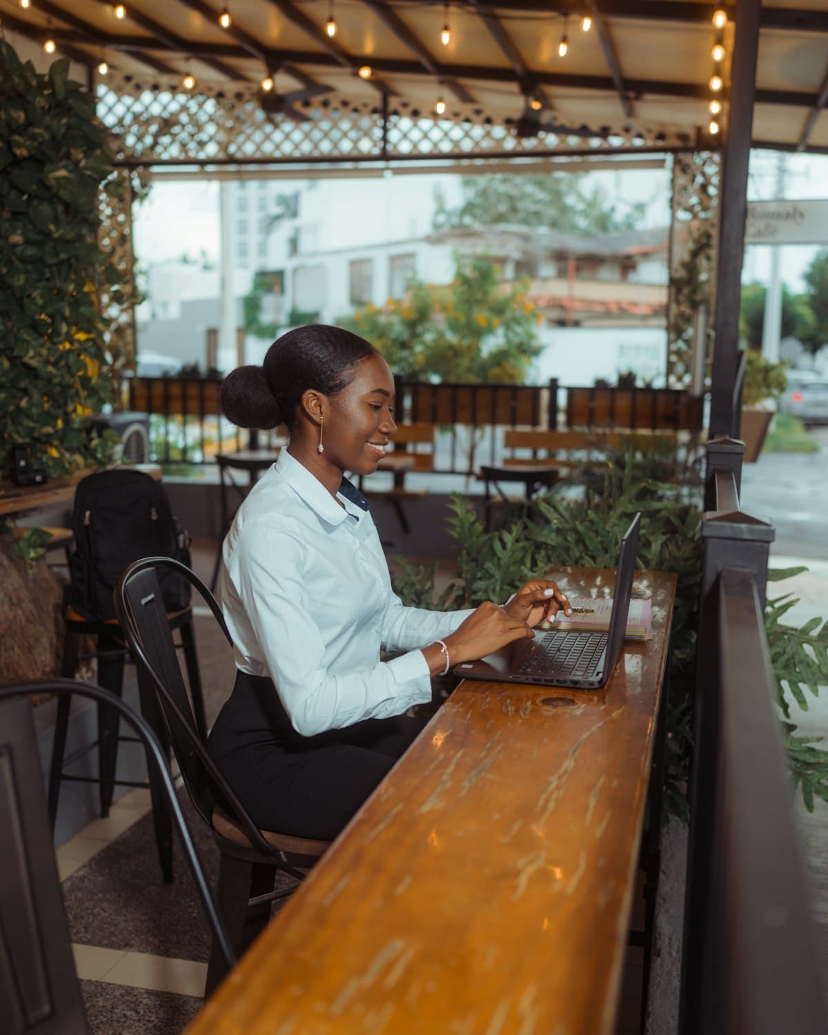Business owner smiling while managing her orders on a laptop at her café counter